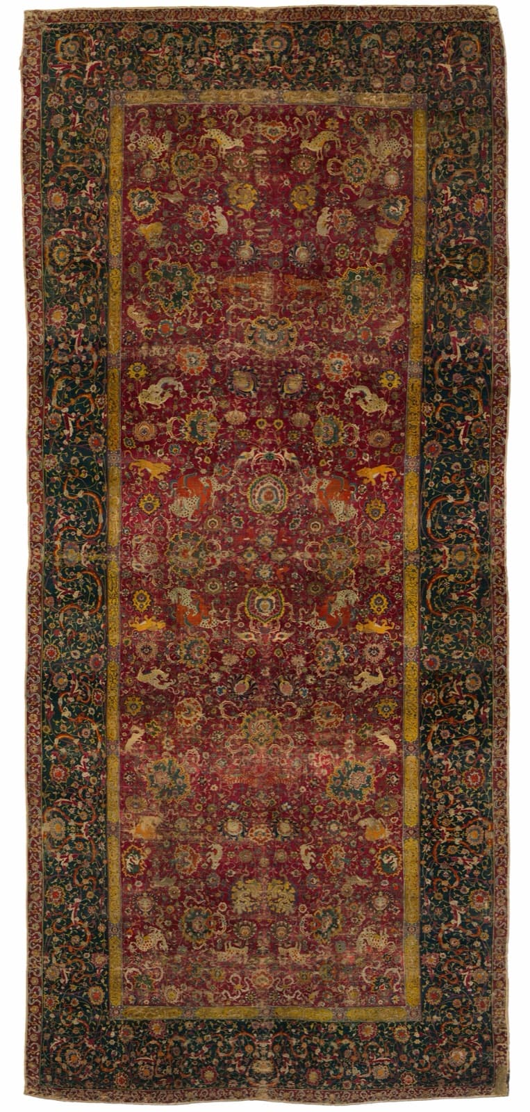 A long carpet with a deep red field of scrolling vines, animals and blossoms, framed by a dark green border.
